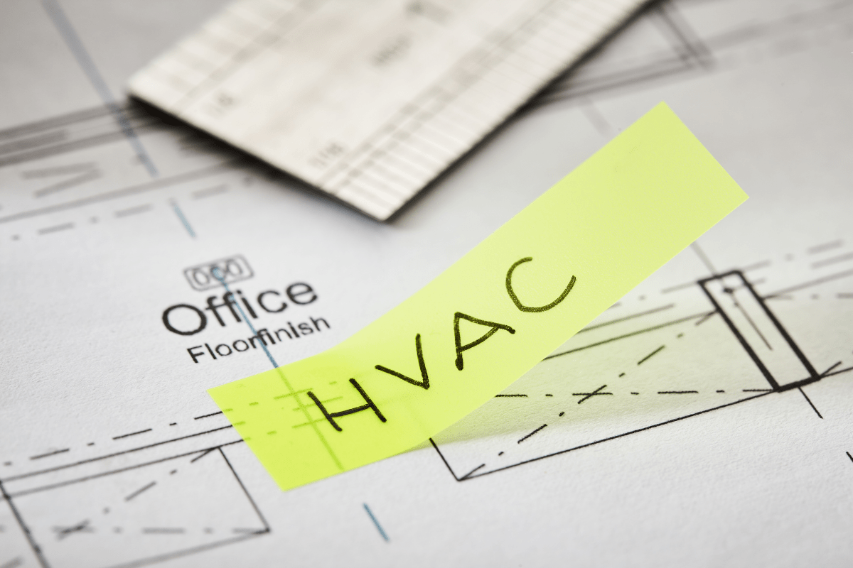 A blueprint of an office space with a piece of paper that has "HVAC" written on it.