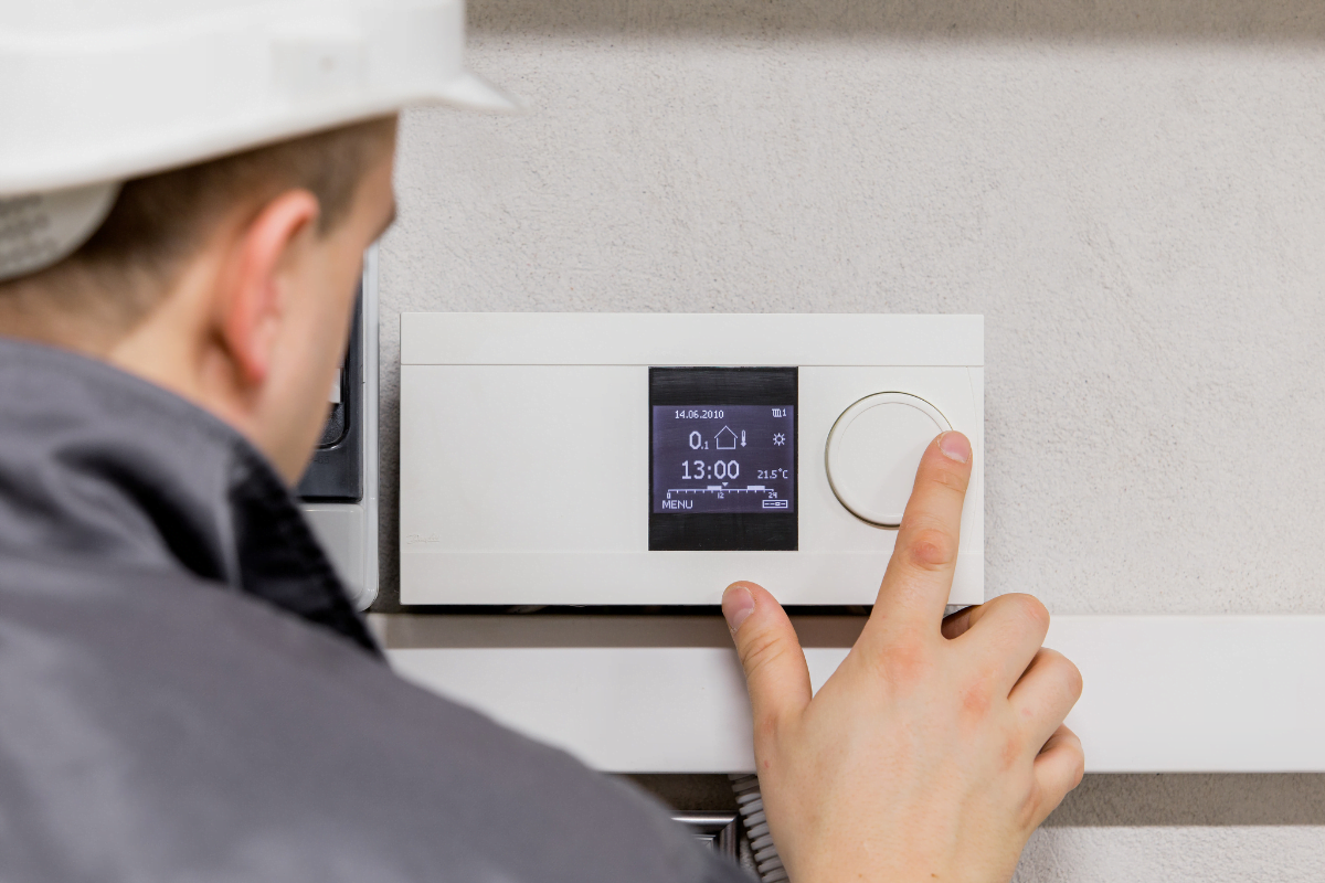 An HVAC specialist adjusting the thermostat.