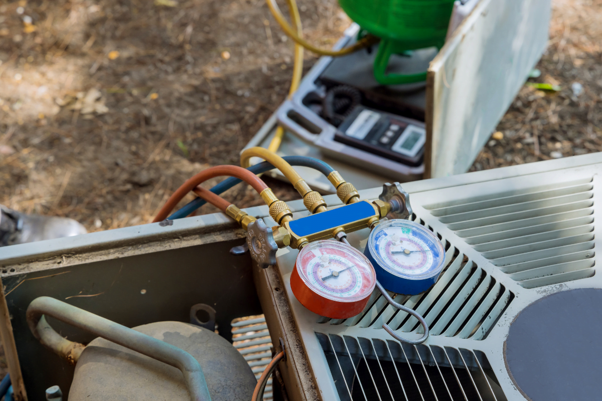 A pair of HVAC manifold gauges on top of an air conditioner.