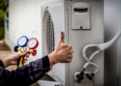 An HVAC expert from Decatur HVAC Services showing an "okay" sign with his hand with an HVAC system in the background.