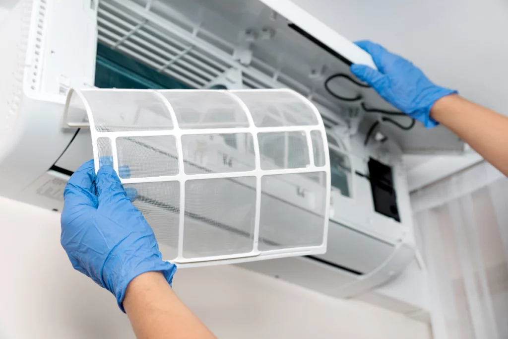 Stay Cool And Save Cash: The Top Benefits Of Commercial Preventative AC Maintenance 1 An HVAC technician replacing the filter of an AC unit.