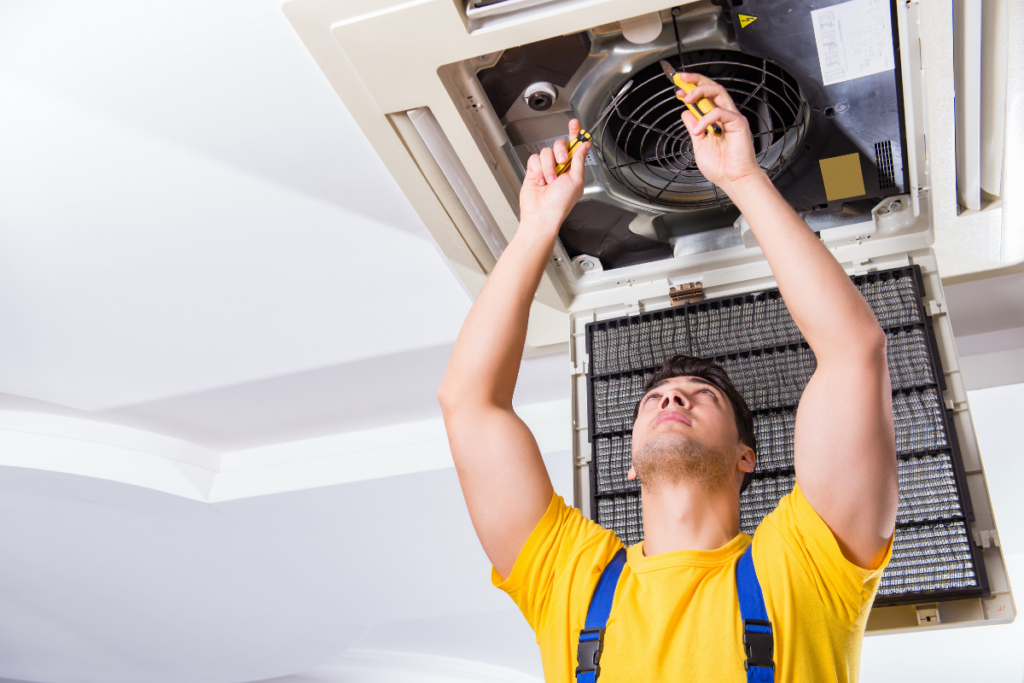 An HVAC professional performing AC maintenance to beat the heat and save cash.