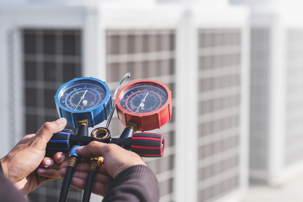 A pair of hands holding HVAC manifold gauges for HVAC maintenance, checking indoor air quality.